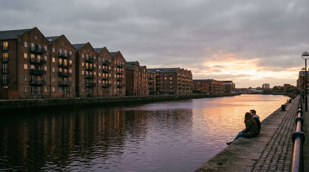 City river embankment lined with old brick warehouses converted to apartments, sunset