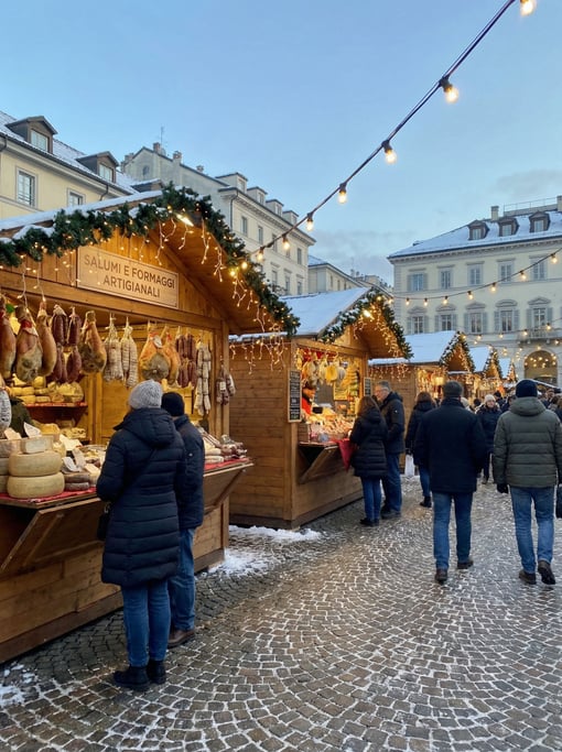 Christmas market with wooden chalets with hanging cured meats and cheeses