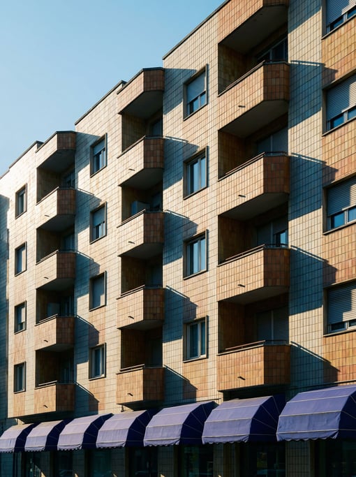 Glazed ceramic tile apartment building with deep geometric shadow patterns from raking light