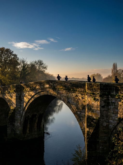 Historic stone arch bridge on a clear day, sharp shadows and bright highlights under blue sky