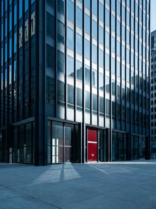 Miesian glass and steel office tower with deep geometric shadow patterns from raking light
