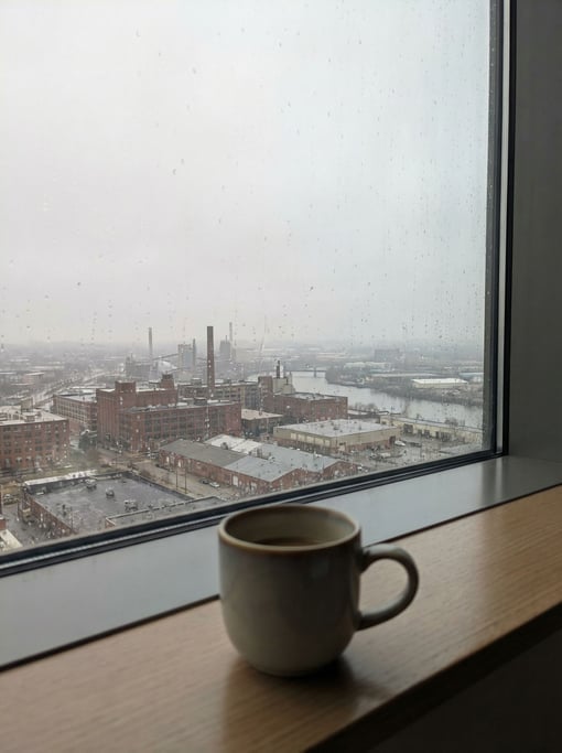 View through a hotel room window on a high floor overlooking a industrial cityscape at overcast midd