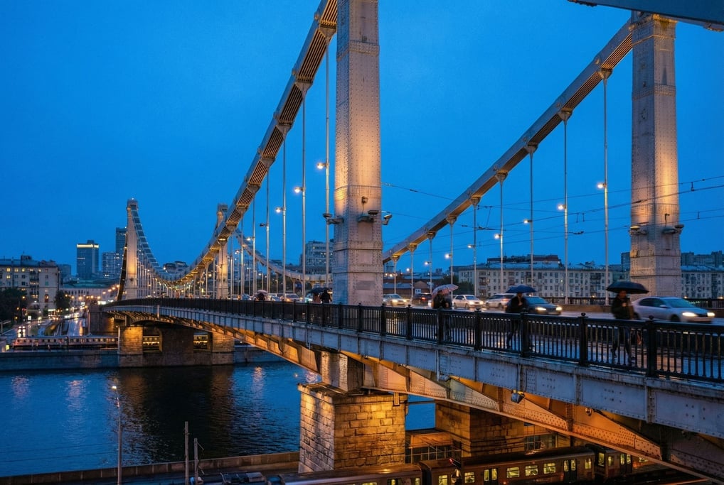 Suspension bridge spanning a wide river at blue hour, riveted steel beams and industrial character