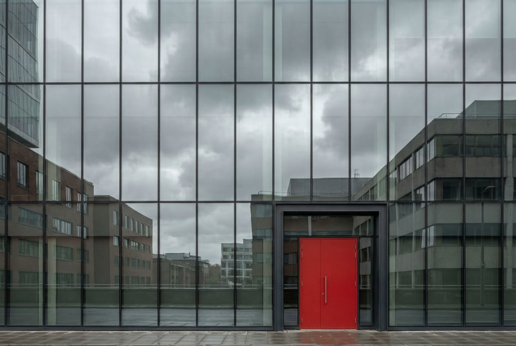 Glass curtain wall reflecting clouds with reflections of surrounding buildings in the glass
