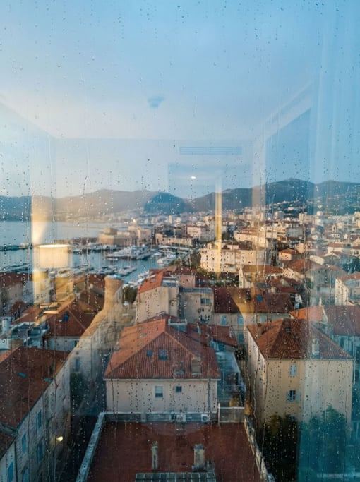 View through a hotel room window on a high floor overlooking a Mediterranean cityscape at early morn