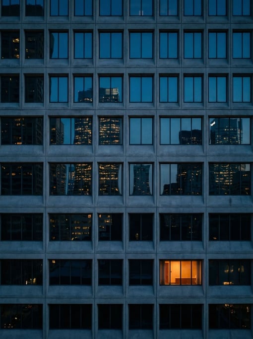 Modernist grid of identical windows with reflections of surrounding buildings in the glass, dusk