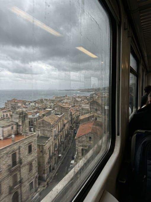 View through a train window speeding past the city overlooking a Mediterranean cityscape at cloudy a