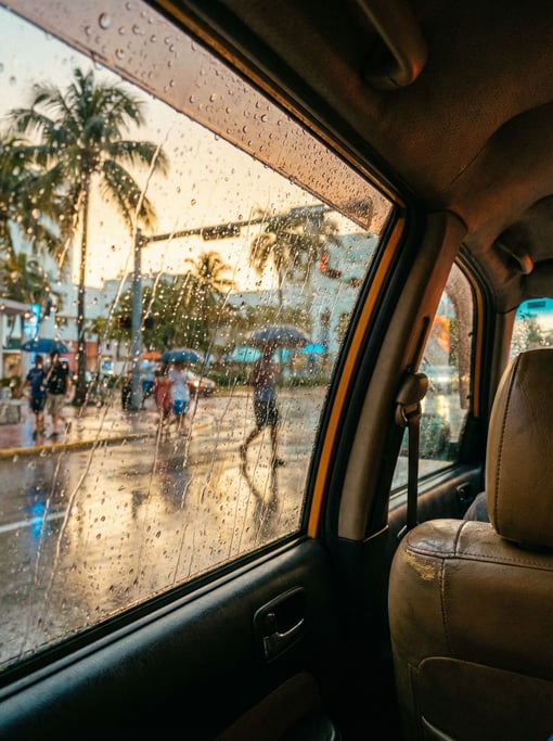 Looking out through a rain-streaked taxi window at a tropical city street