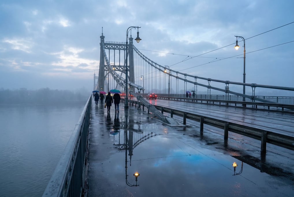 Suspension bridge spanning a wide river after rain, wet pavement reflecting lights and sky