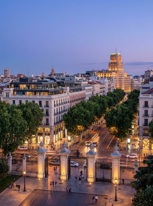 Cinematic wide shot of the Retiro Park entrance with the city visible beyond in Madrid at blue hour