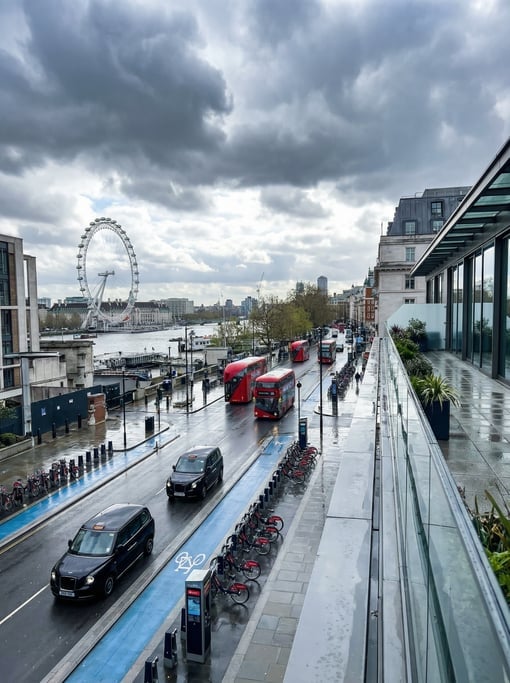 Elevated view from a rooftop terrace overlooking a rainy Mayfair street with modern black cabs and r