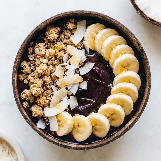 Overhead shot of an açaí bowl with deep purple-black base topped with sliced banana
