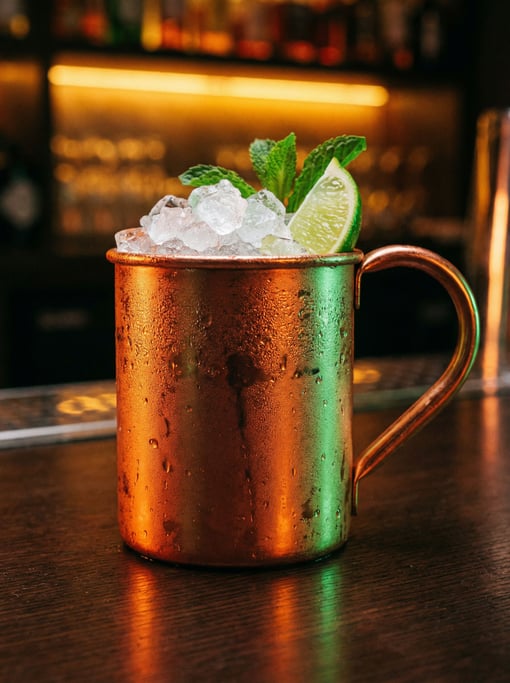 A vertical shot of a copper Moscow mule mug beaded with condensation
