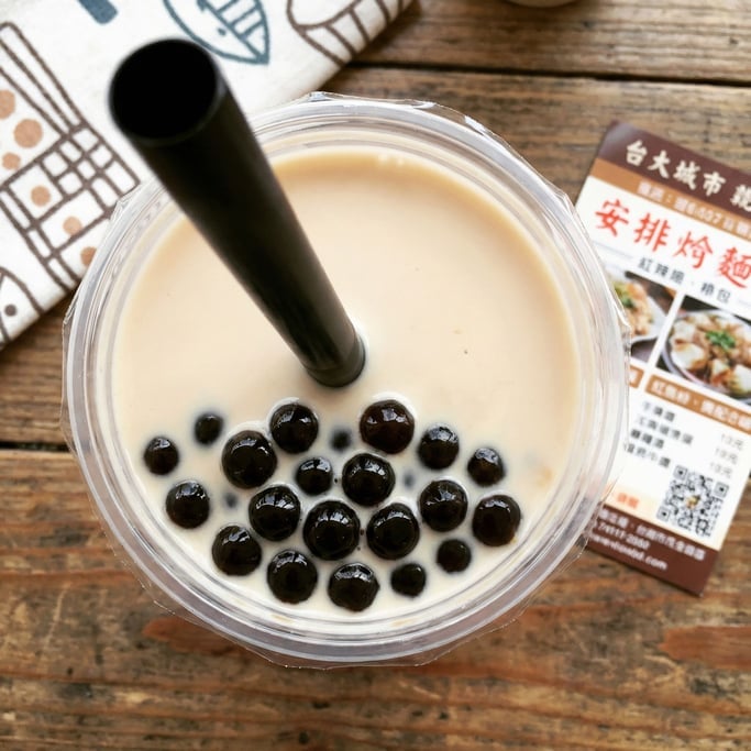 Bubble tea in a clear cup from above — the dark tapioca pearls settled at the bottom beneath creamy