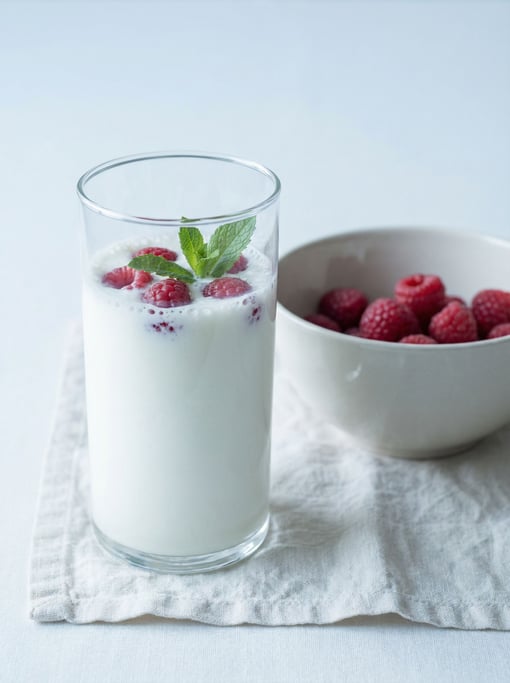 A tall glass of kefir, the thick fermented milk drink opaque white with a slight effervescence visib