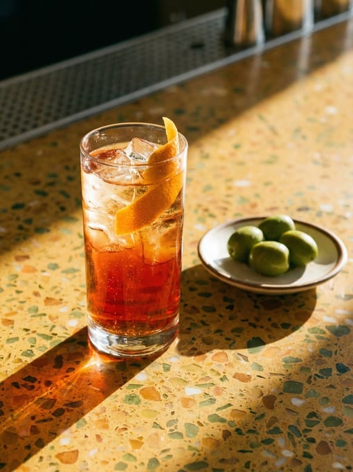 Tall shot of vermouth and soda in a highball glass with ice and an orange peel