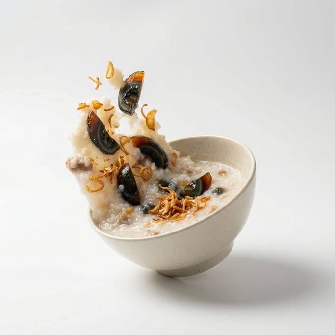 A bowl of congee rice porridge with century egg and crispy shallots, floating in mid-air