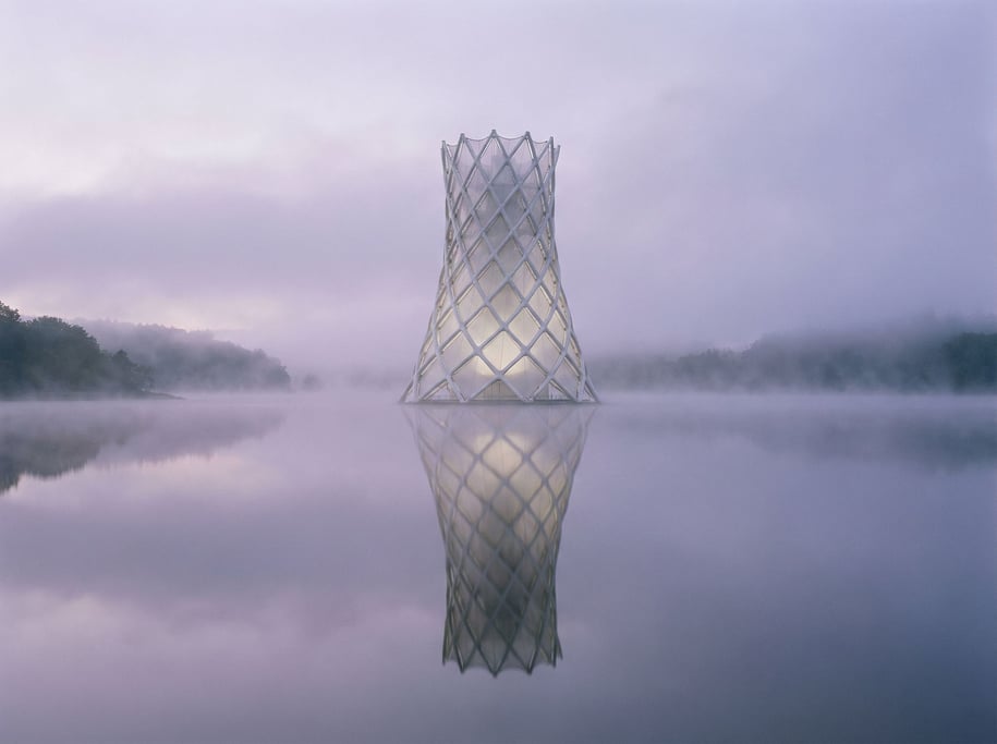 A biomorphic tower rises from a misty lake at dawn