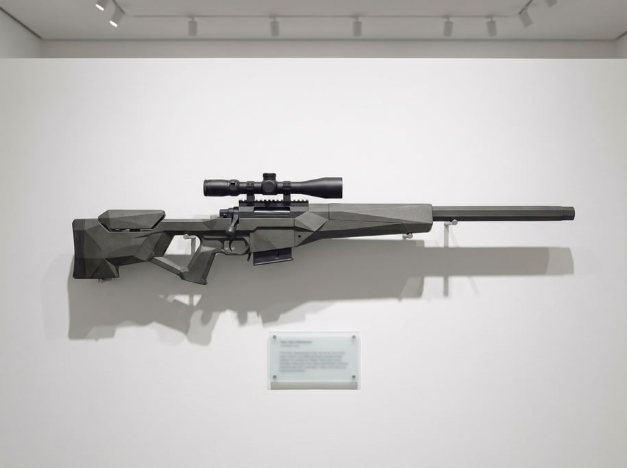 A long-range rifle in dark composite with an integrated optic scope displayed on pegs against a whit