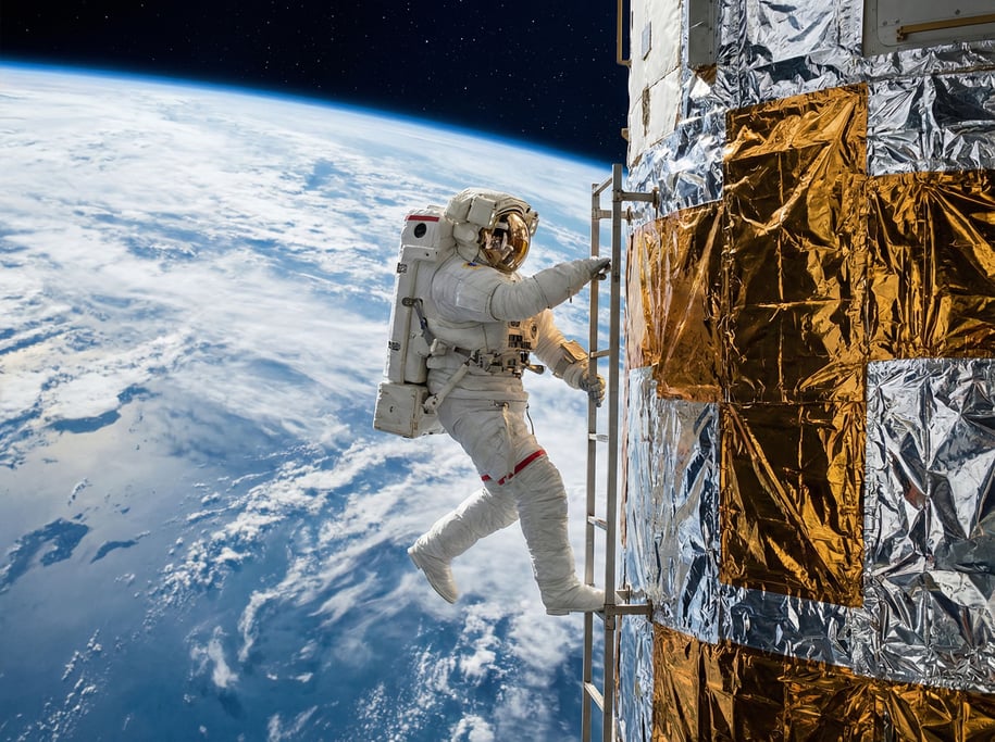 A figure in a full EVA suit climbs a ladder on the exterior of a space station module