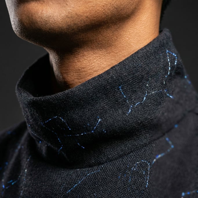 Close-up of a neck and collar area — the garment is a high-necked piece in dark material with embedd