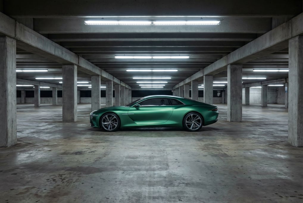 A concept coupe in matte emerald green sits alone in an empty multi-story parking garage