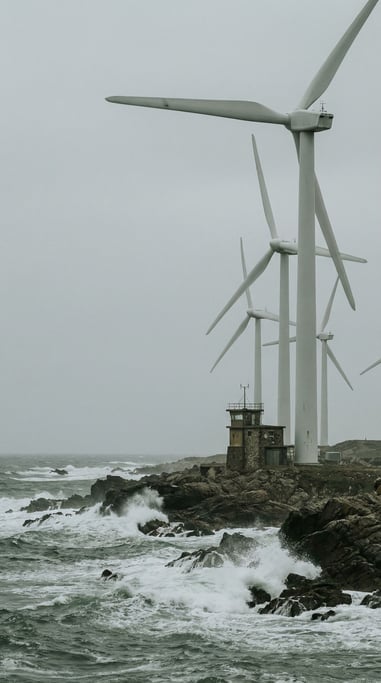 Wind turbines on a rocky coastline at overcast midday