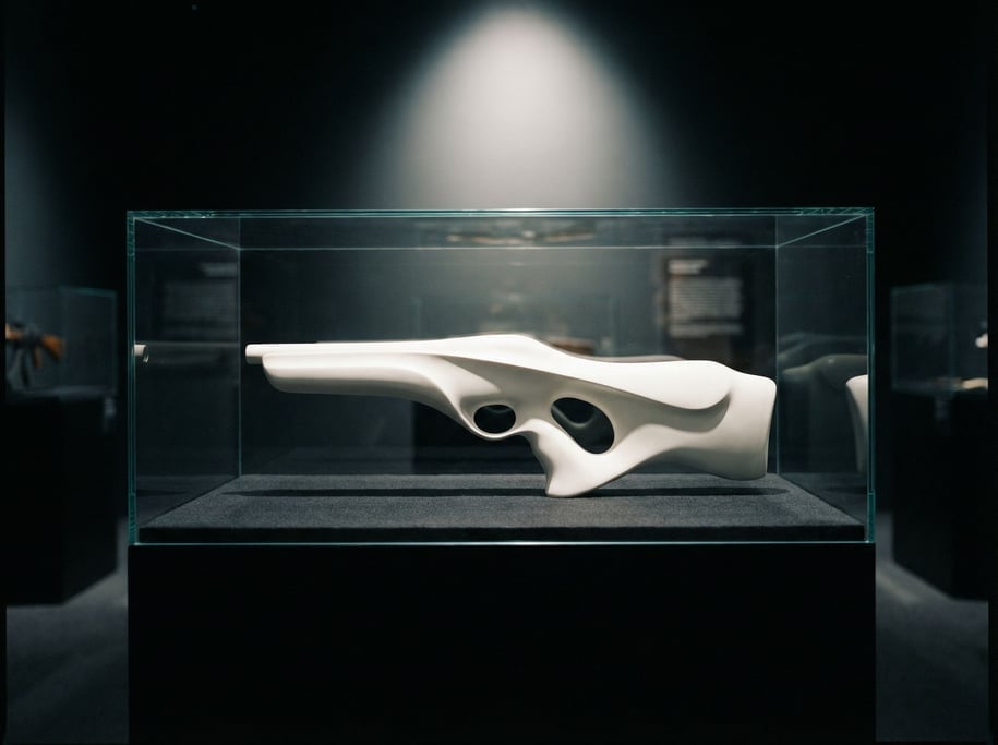 A sculpted weapon displayed in a glass case on a dark felt surface — a smooth white composite form w