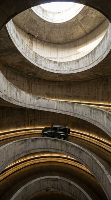 A vertical shot looking down a deep concrete shaft with a spiral ramp descending along its inner wal