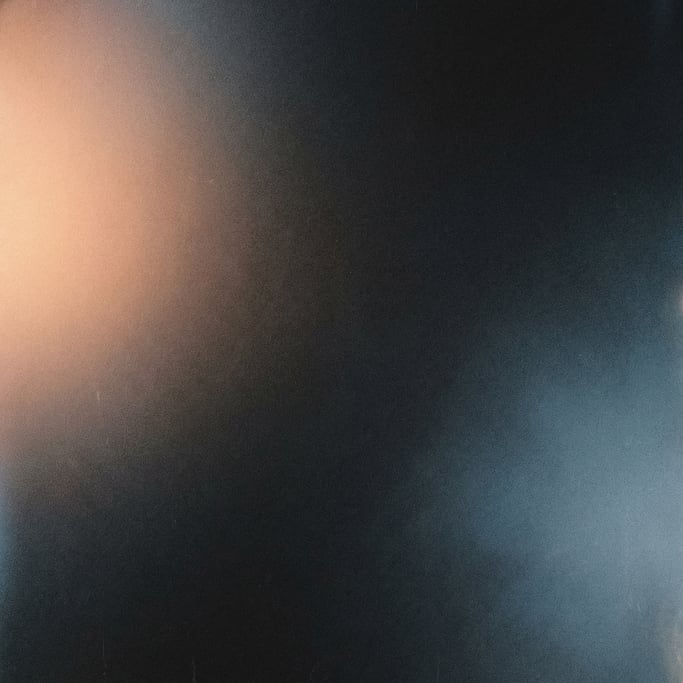 Moody film grain gradient, near-black background with opposing corner glows of warm peach in upper l