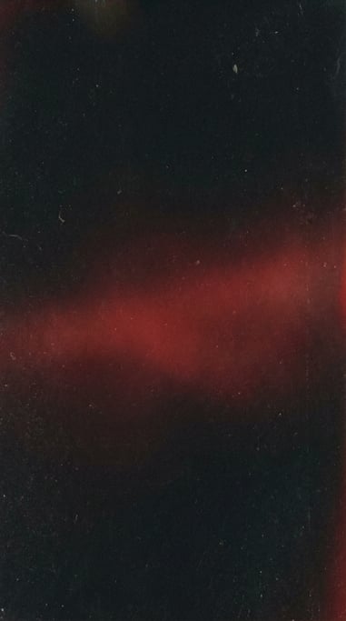 Dark grainy gradient abstract, near-black canvas with a soft glowing band of deep scarlet red across