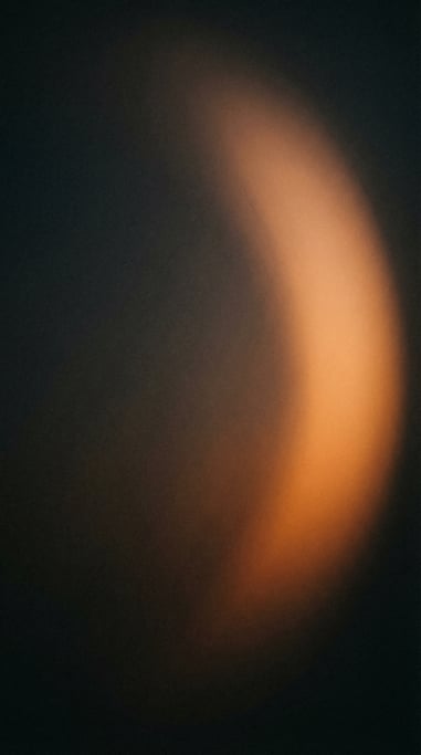 Moody dark gradient atmosphere, near-black background with a diffused arc of warm apricot light swee
