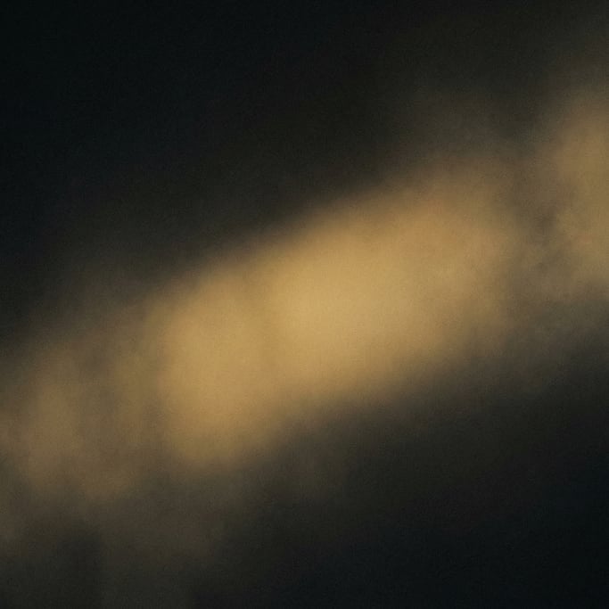 Dark moody gradient with noise, near-black background with a diffused diagonal glow of warm honey go