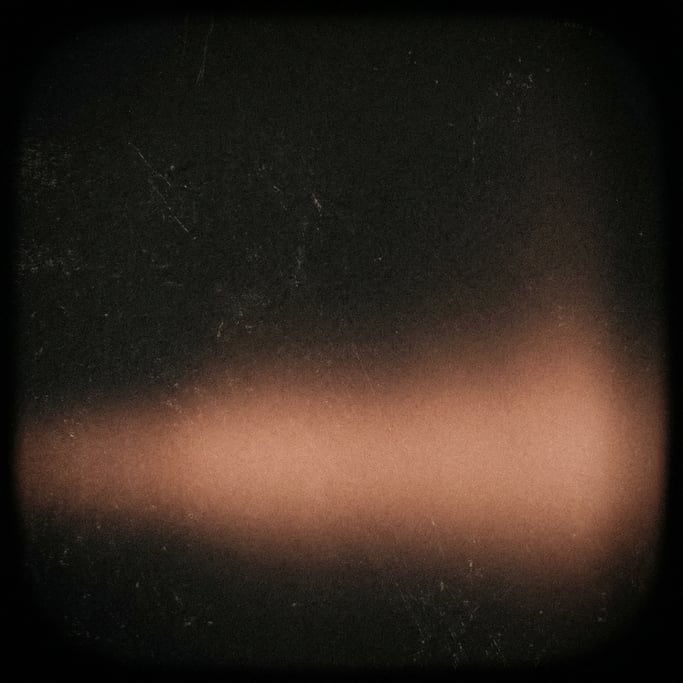 Moody film grain gradient, near-black canvas with a wide soft glow of warm terracotta along the bott