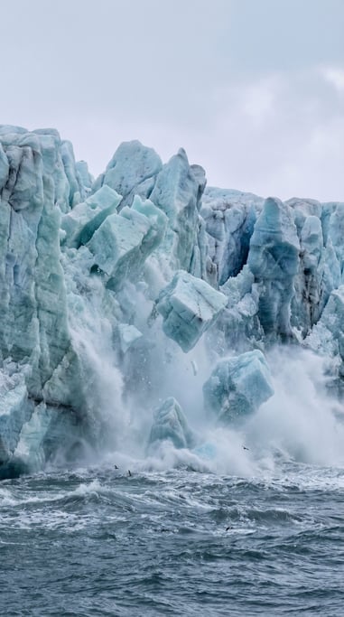 Massive wall of ice rendered in blues from pale cyan to deep navy — a glacier calving into the sea