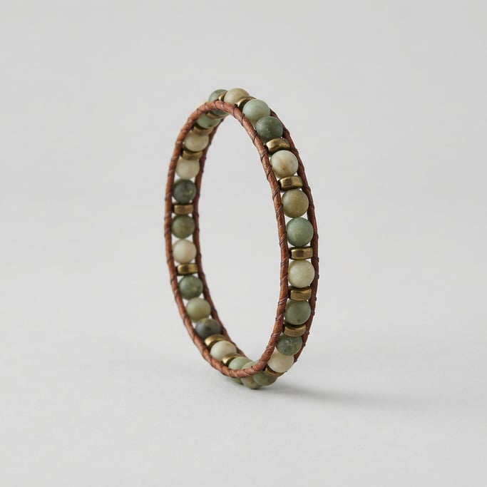 Beaded wrap bracelet with matte jade stones and small brass spacer beads strung on braided leather c
