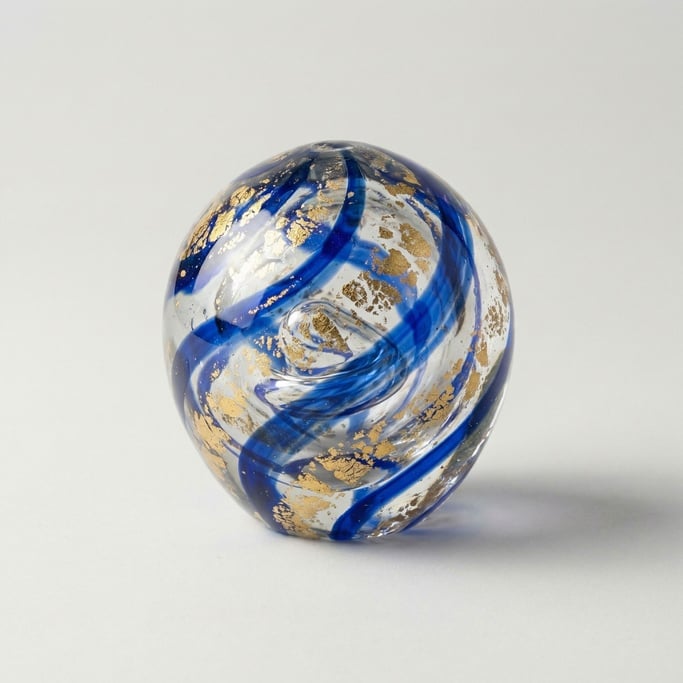 Hand-blown glass paperweight with swirling cobalt blue and metallic gold leaf inclusions trapped ins