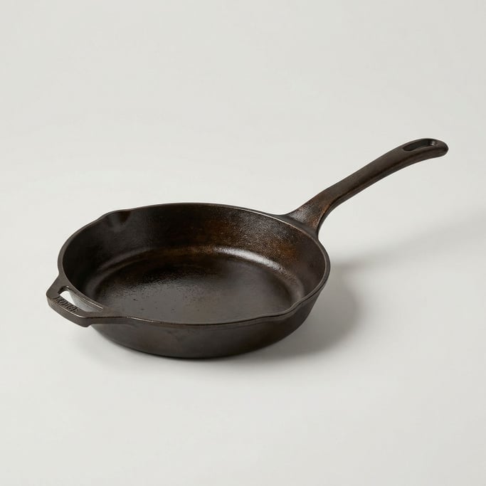 Heavy cast iron skillet with a long handle showing well-seasoned natural patina and a smooth cooking