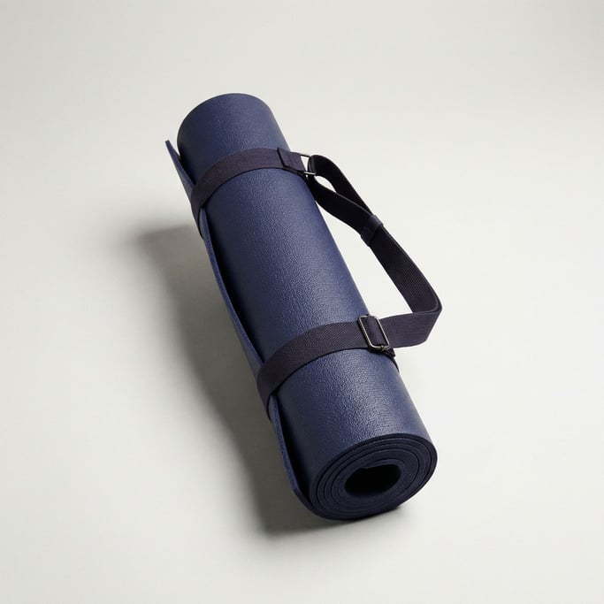 Rolled yoga mat in deep indigo textured rubber, bound by an elastic fabric carry strap with buckle