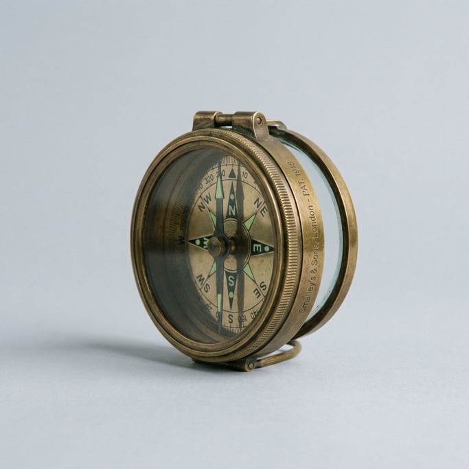 Brass orienteering compass with a hinged glass lid, luminous cardinal points