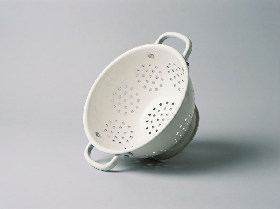 Cast aluminum colander in matte white enamel finish with star-shaped perforations and two riveted si
