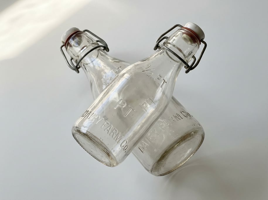 Vintage-style milk bottle in thick clear glass with a ceramic swing-top bail cap and embossed measur