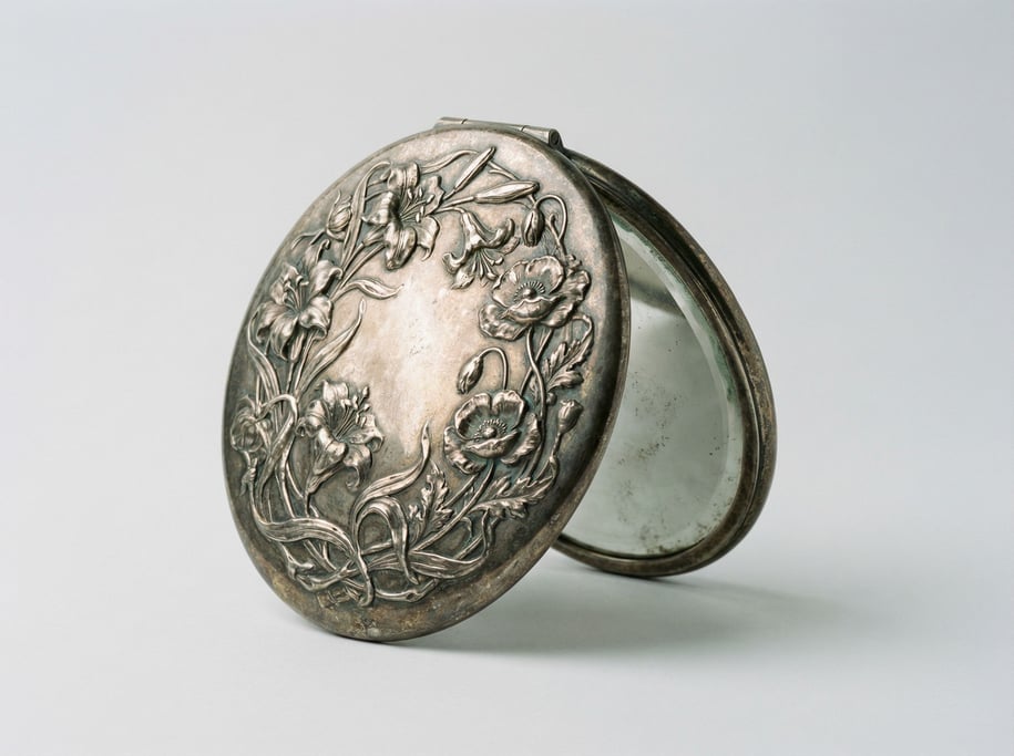 Art nouveau hand mirror in tarnished sterling silver with a high-relief floral vine pattern on the o