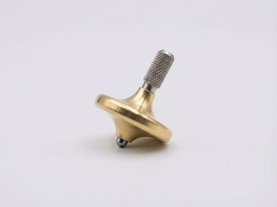 Brass spinning top with a knurled grip stem, polished mushroom-shaped body