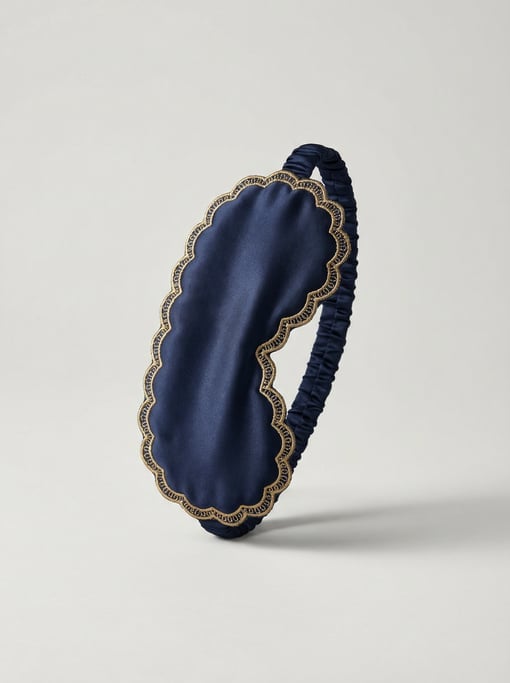 Silk sleep mask in midnight navy satin with gold embroidered scalloped edges and an adjustable elast