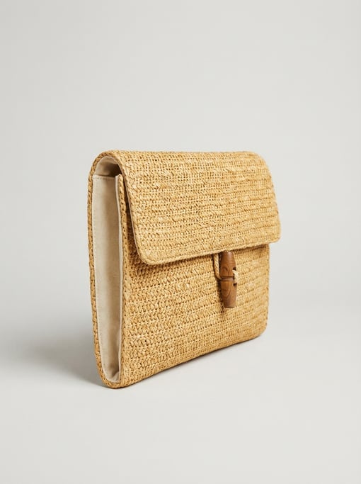 Woven raffia clutch bag in natural golden straw color with a carved wooden toggle clasp and cotton l