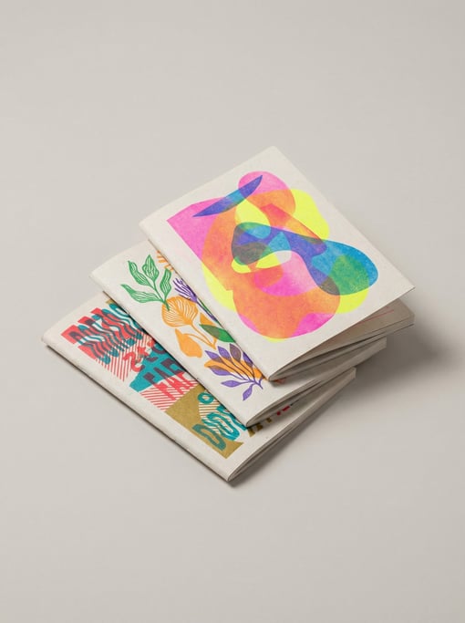 Stack of three small art zines with colorful risograph-printed covers