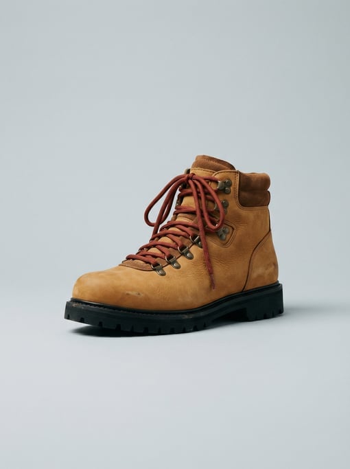 Rugged hiking boot in tan nubuck leather with rust-red woven laces, a lugged rubber outsole
