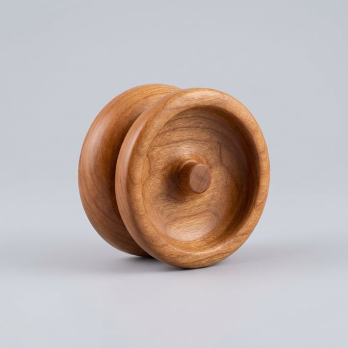 Wooden yo-yo in natural cherry with a polished face, precision recessed string gap