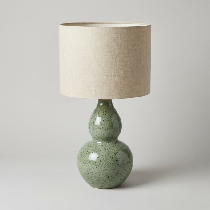 Ceramic table lamp base in speckled sage green glaze with a gourd-shaped body and a natural linen dr